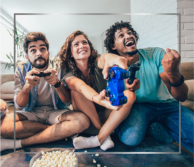 Një grup njerëzish të buzëqeshur që janë ulur në tokë duke luajtur videolojëra, të lumtur pas trajtimit të infeksionit mykotik të lëkurës me Canesten®